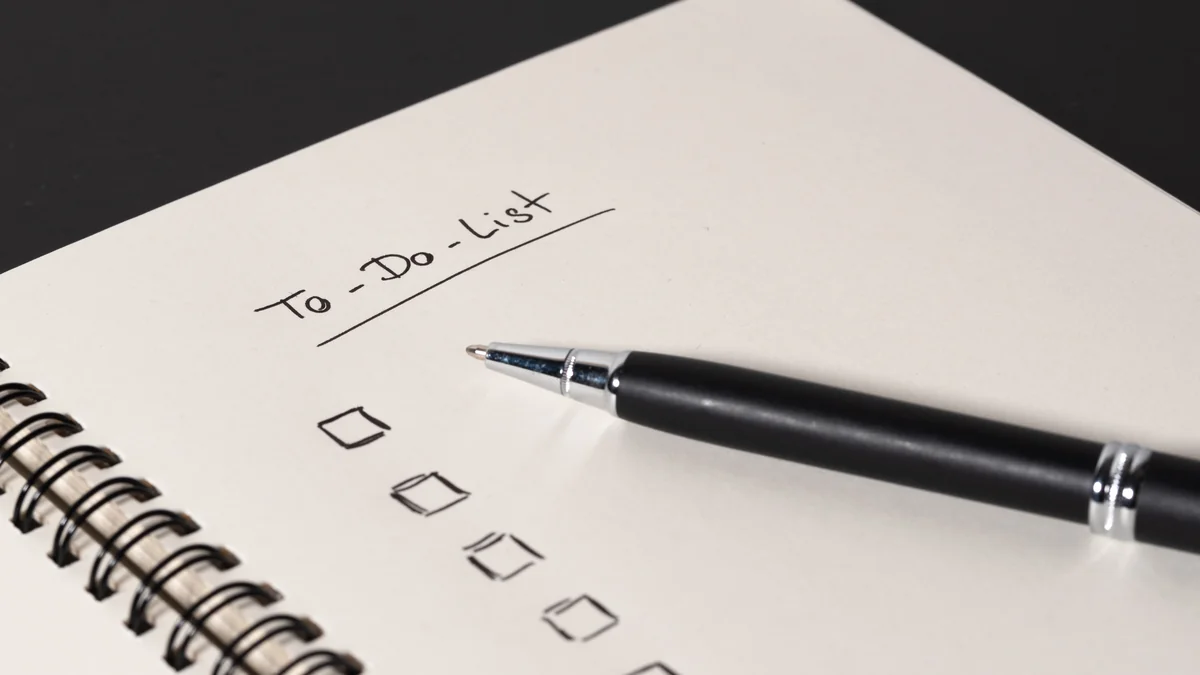 A spiral notebook page headed "To-Do List" with empty checkboxes and a pen