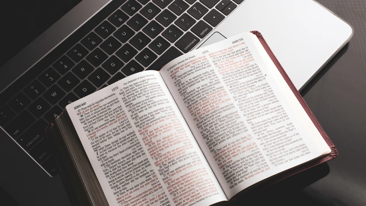 An open Bible resting on a laptop keyboard